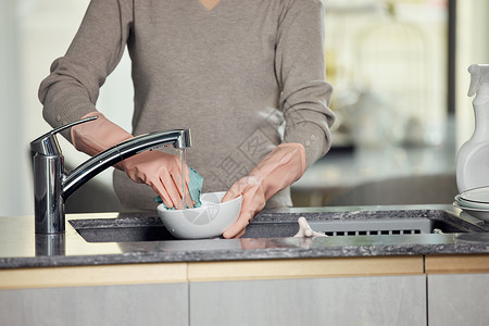 手握洁具刷碗的女性手部特写背景