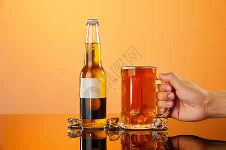 四个彩色气泡用手拿起放在桌面上的冰镇啤酒杯背景
