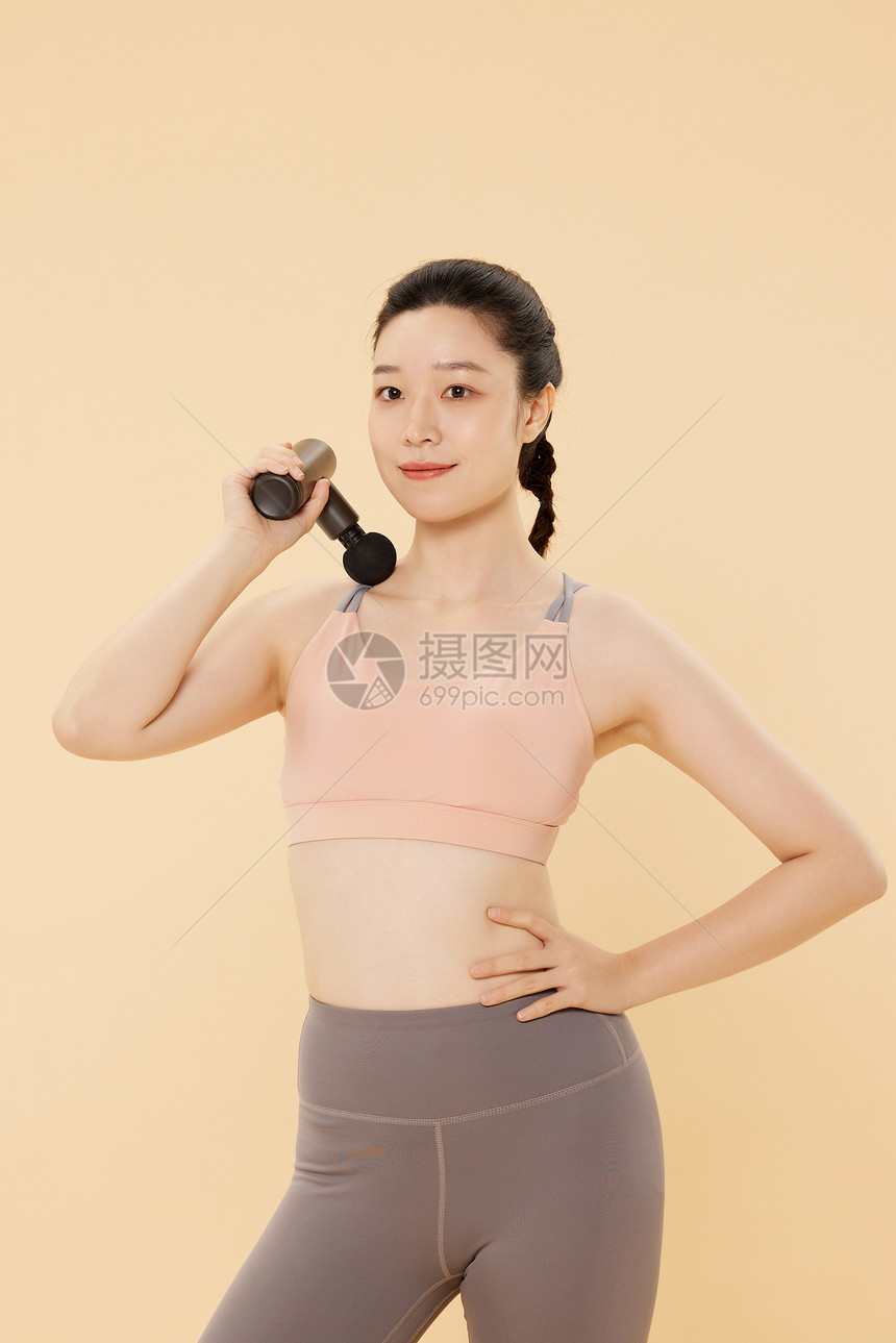 健身女性使用筋膜枪放松肩部肌肉图片