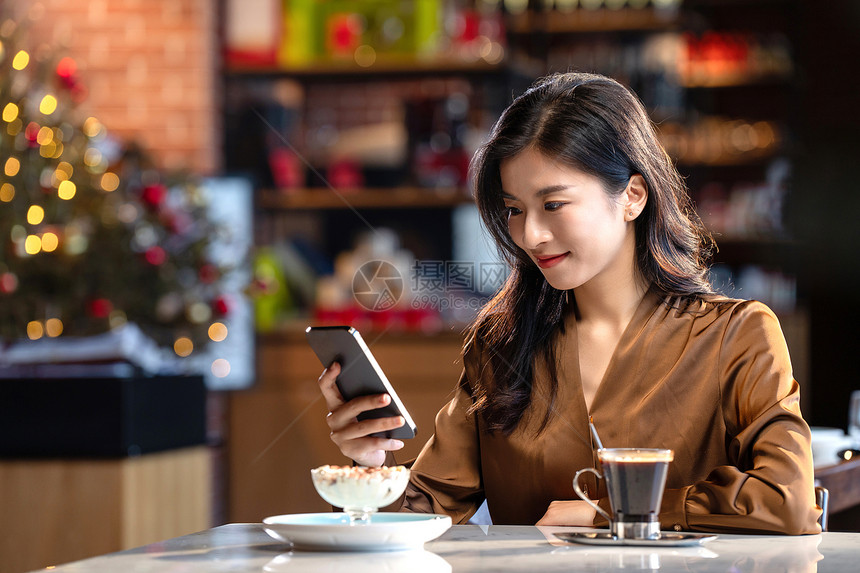 咖啡馆内边喝咖啡边使用手机的青年女人图片