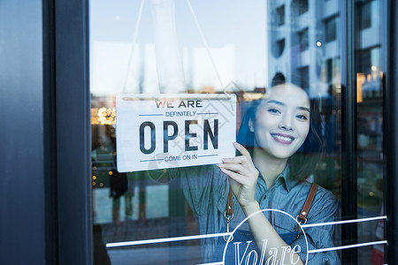 营业通知咖啡店的女服务员挂营业标志背景