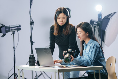 两个摄影师在工作室里讨论工作的青年女摄影师背景
