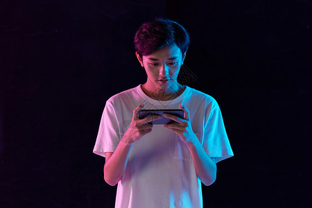 手机网游使用手机玩游戏的年轻男性背景