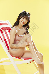 泳装美女沙滩椅涂抹防晒霜背景图片
