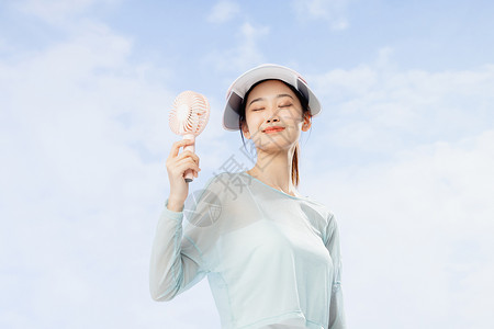 羽毛球服手拿小风扇身着防晒服的夏日美女背景