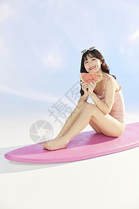 泳装美女拿着西瓜坐在冲浪板上高清图片