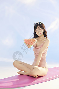 泳装美女拿着西瓜坐在冲浪板上高清图片
