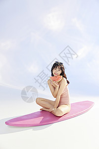 拿着西瓜坐在冲浪板上的泳装美女高清图片