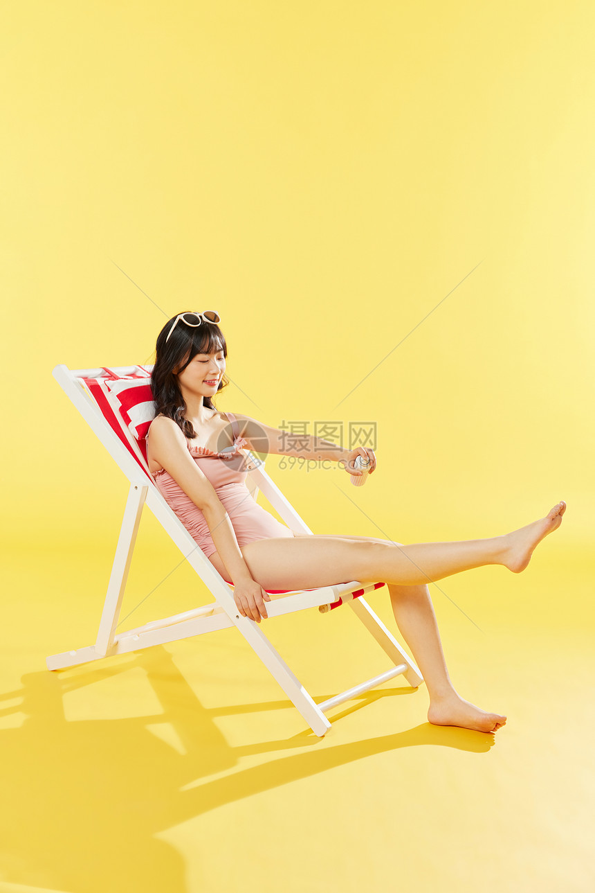 泳装美女沙滩椅涂抹防晒霜图片
