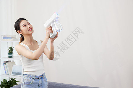 年轻女性使用喷雾机消毒图片
