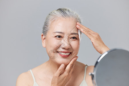 对着镜子护理皮肤的老年女性图片