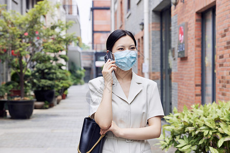 戴口罩的商务女青年室外打电话背景图片