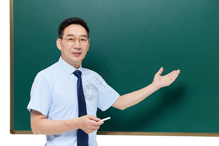 中年教授手拿粉笔站在黑板前上课图片
