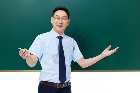手拿粉笔站在黑板前的中年教授图片