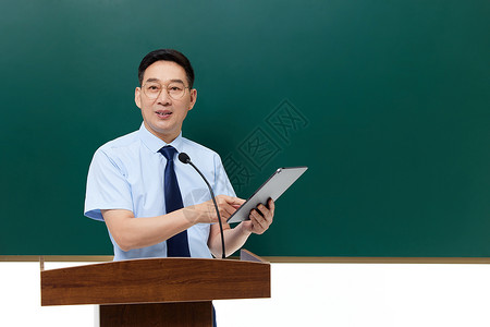 讲台上的老师男教授手拿平板电脑站在讲台上背景
