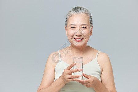 手捧水杯的老年女性背景图片