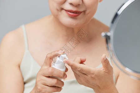 老年女性涂抹乳液特写图片