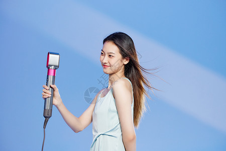 用吹风机吹头发的美女背景图片
