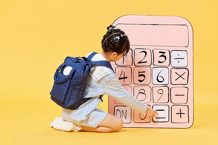 背着书包使用大号计算器的小女孩高清图片