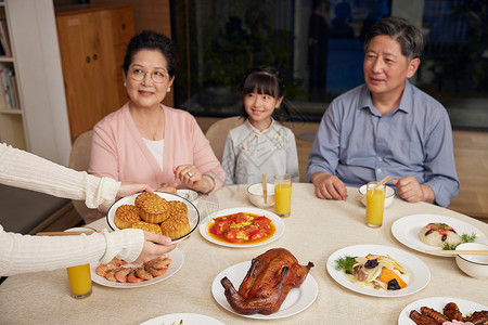 中秋家庭聚餐妈妈手端月饼背景图片