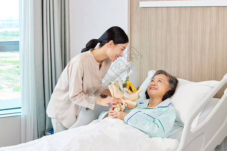 青年女性手拿花束探望生病住院的老人图片