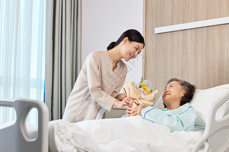 手拿花束的女性探望生病住院的老人背景图片