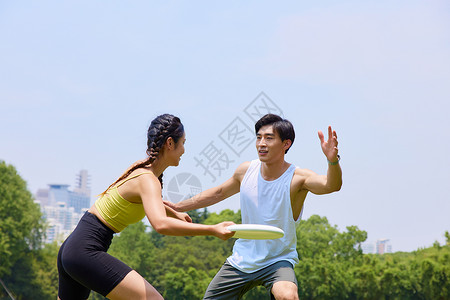 户外玩飞盘的青年情侣背景图片