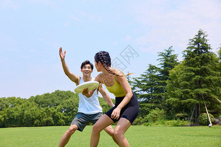 体育游戏青年情侣在户外玩飞盘背景
