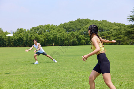 青年男女在公园玩飞盘高清图片