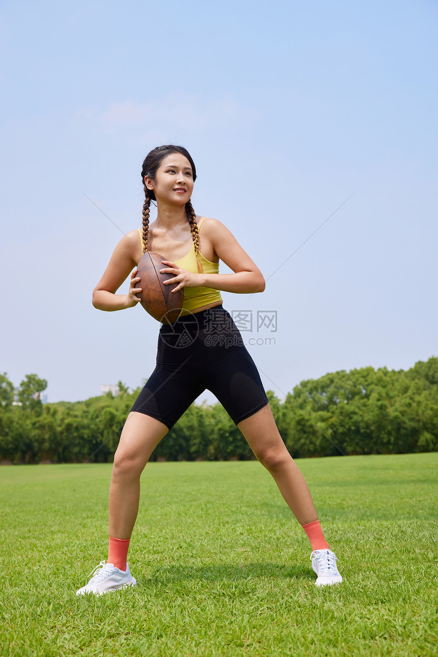 年轻美女户外草坪玩橄榄球图片