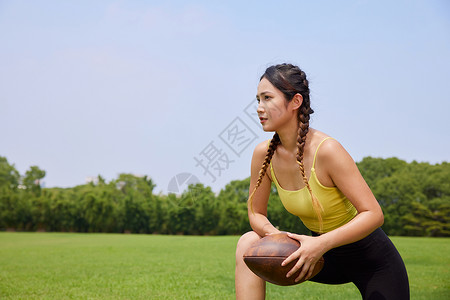 年轻美女户外玩橄榄球图片