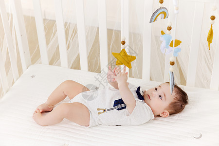 可爱宝宝在婴儿床上玩床铃图片