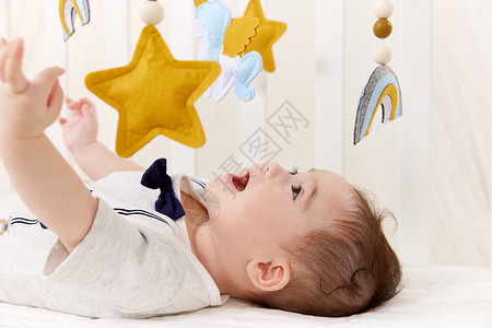 初生宝宝在婴儿床上玩摇铃图片
