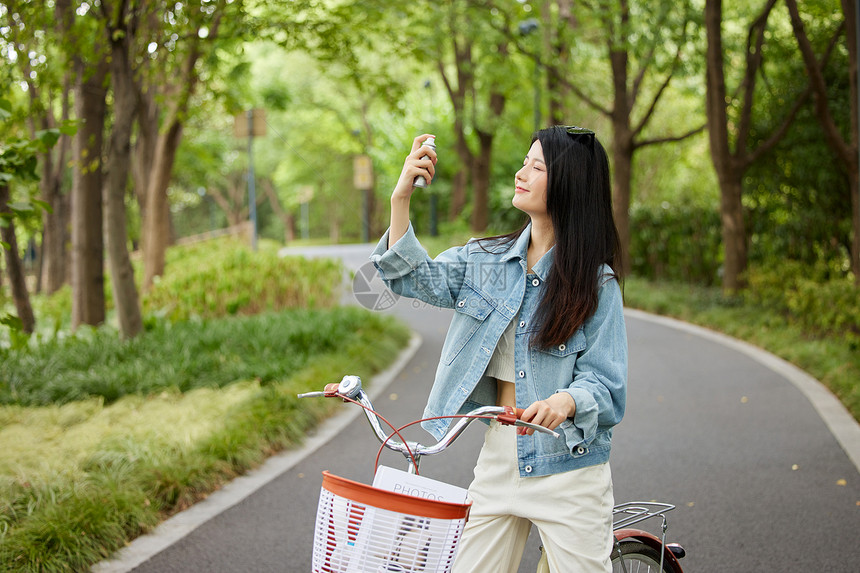 公园骑行的美女使用补水喷雾图片