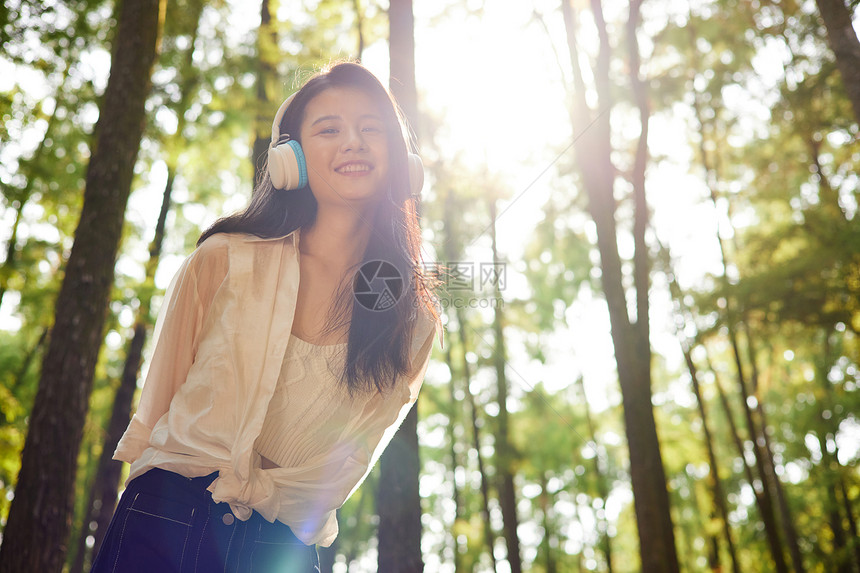 夕阳下在树林里散步玩耍的美女图片