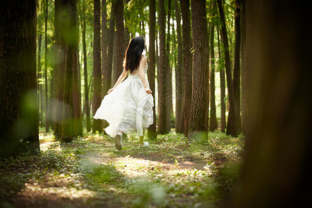 穿着白色长裙在树林奔跑的美女背影背景图片