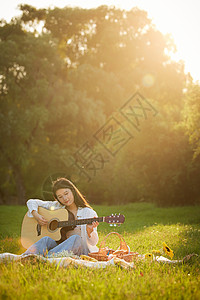 阳光下的美女草地上弹吉他图片