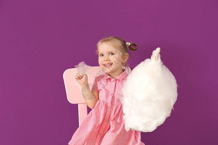 可爱的小女孩拿着棉花糖坐在椅子上图片