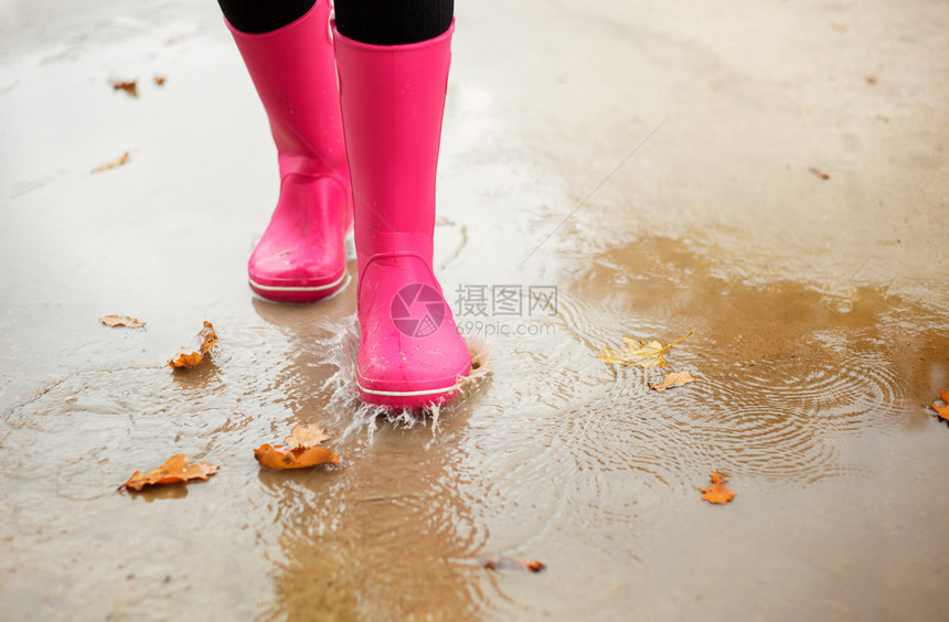 下雨天穿着粉红色橡胶雨靴走在水坑图片