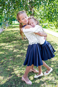 两个可爱的微笑小女孩在他们的学校前摆姿势可爱的小孩对重返学校图片