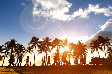 日落时在拥挤的卡拉瓦大街上行走的人剪影夏威夷檀香山威基海滩的前步行街长廊增强的阳光暖滤光片与镜头光晕作为背景图片