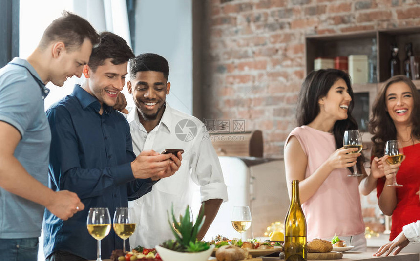 男朋友在家里聚会时使用智能手机和饮酒料的图片