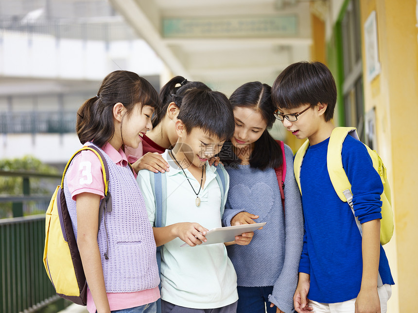 一群亚裔学生在学校走廊看电脑平图片