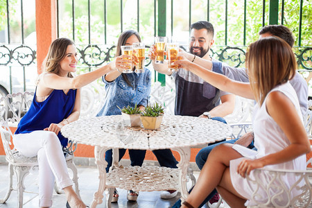 迷人的西班牙裔年轻朋友为庆祝友谊而举杯敬酒图片
