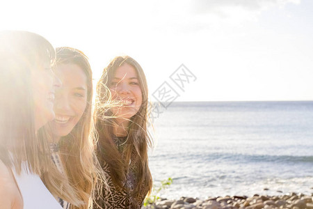 三位年轻的女性朋友在海滩一起散步聊天图片