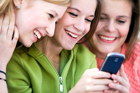 三位女性朋友笑着看向手机图片