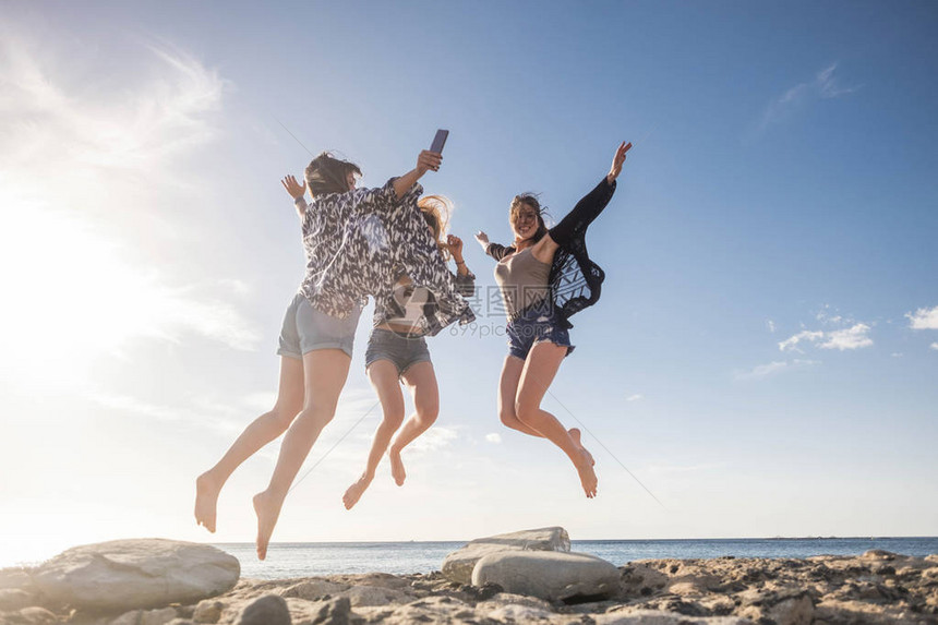 三个漂亮的年轻女子为乐趣和幸福而跳跃图片