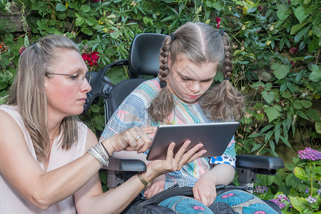 一名坐在轮椅上的残疾儿童与一名志愿护理人员一起图片