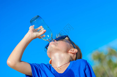 在沙漠热带海滩上喝水的太阳镜里长着口渴的英图片