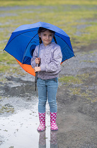小女孩在雨伞下玩耍图片